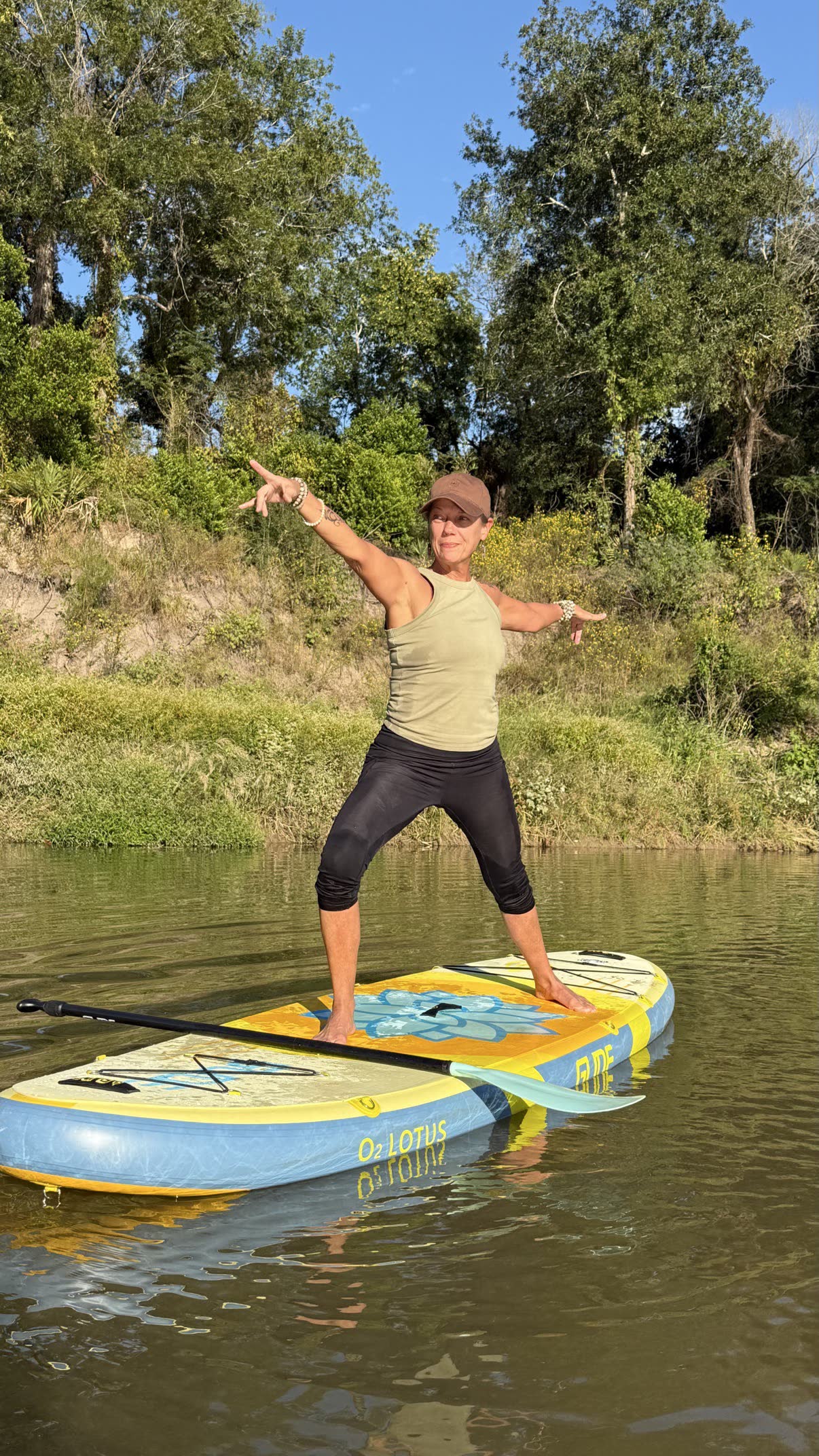 Yoga instructor holding Warrior II pose on the natural white sand beside the river bend